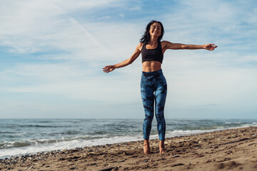 A beautiful brunette girl is dancing on the beach by the sea on the sand