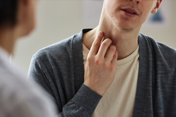 Close up of man pointing at neck skin during consultation with dermatologist in clinic, copy space