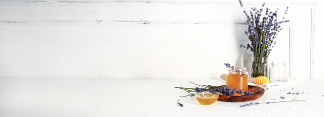 Jar and glass bowl of sweet lavender honey on white background with space for text