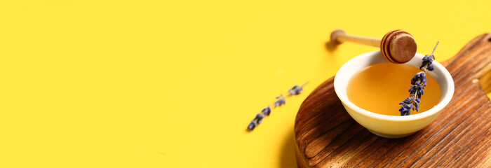 Fototapeta premium Bowl of sweet lavender honey and dipper on yellow background with space for text
