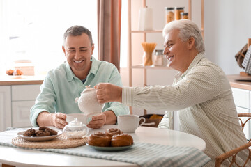 Mature brothers drinking tea in kitchen