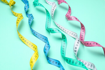 Colorful measuring tapes on turquoise background
