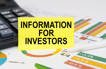 Naklejka premium On business reports there is a calculator and a sign with the inscription - Information for investors