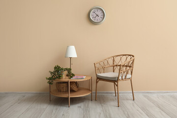 Coffee table with lamp, houseplant and armchair near beige wall
