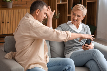 Angry mature man taking his wife's mobile phone at home