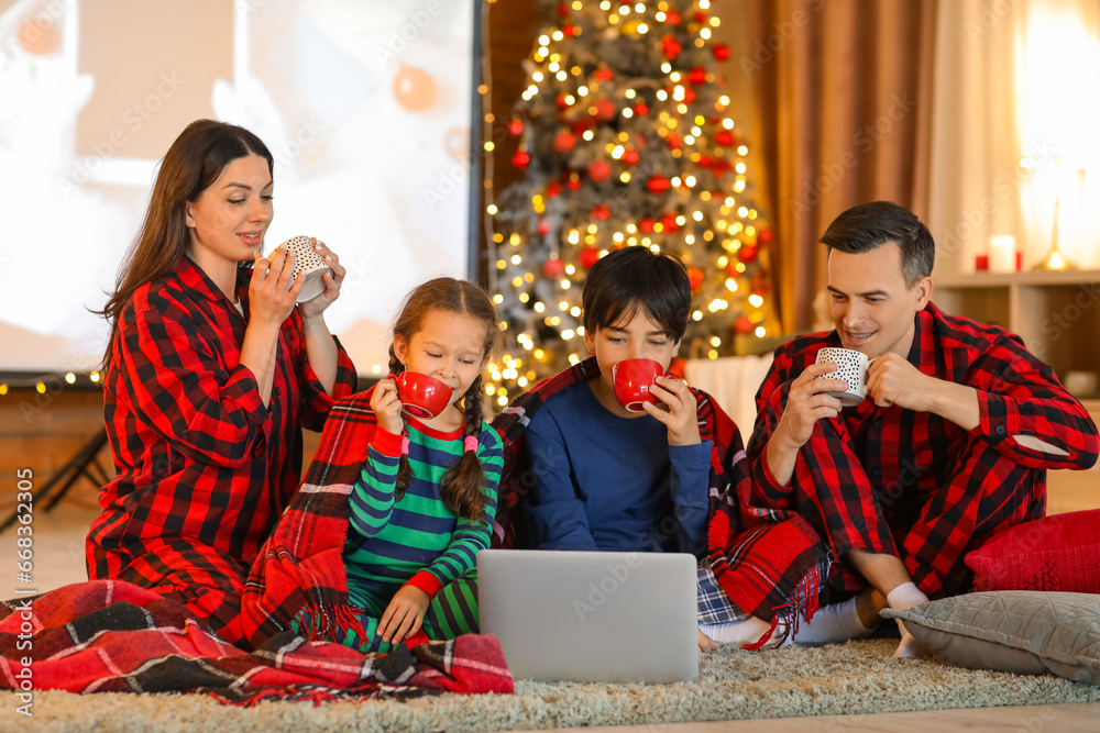 Poster Happy family with cocoa watching Christmas movie on laptop at home