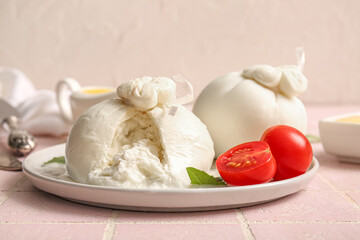 Plate with tasty Burrata cheese on table