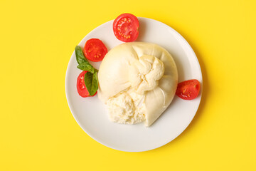Plate with tasty Burrata cheese on yellow background
