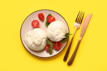Plate with tasty Burrata cheese on yellow background