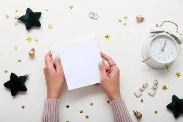 Woman with blank card, jewelry and Christmas decor on beige background