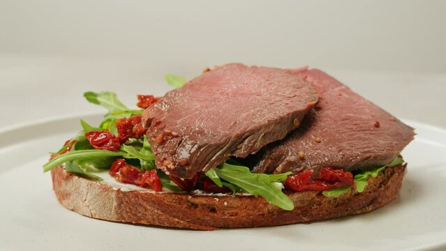 American pastrami sandwich in New York ham meet cuts. chef cooking Famous thick cut sous vide beef sandwich on restaurant cafe kitchen. Bread with curd cheese. Studio shot close up.