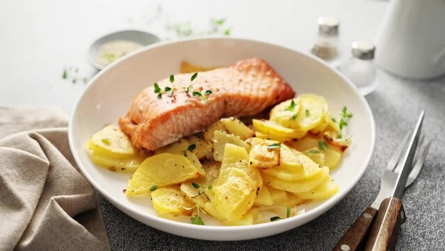 Salmon or trout fillet roasted or baked with potato in the oven. Cooked red fish with vegetables, stock video 4k footage.