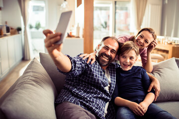 Naklejka na ściany i meble Happy young family taking a selfie at home