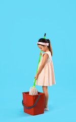 Cute little girl with mop and bucket on blue background