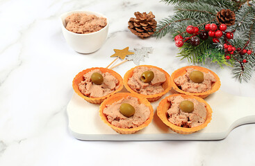 Christmas and New Year's dishes, a set of snacks and refreshing drinks for the holiday table. Plate with tartlets of pate, cheese and olives on a marble table,