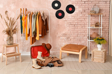 Interior of modern hallway with stylish autumn clothes, suitcase and vinyl disks