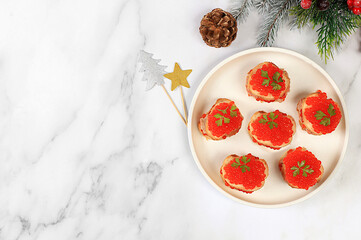 Christmas and New Year's dishes, a set of canapes for the festive table. Plate with tartlets of pate and red salmon caviar on a concrete table,