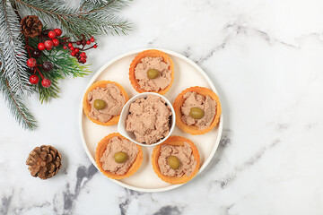 Christmas and New Year's dishes, a set of snacks and refreshing drinks for the holiday table. Plate with tartlets of pate, cheese and olives on a marble table,