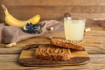 Board of toasts with peanut butter on wooden background