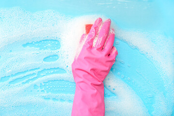 Female hand in pink rubber glove cleaning blue surface with sponge