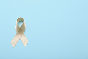 Beige ribbon on blue background. Uterine cancer awareness concept