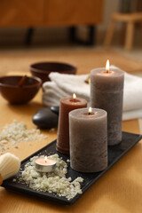 Burning candles with sea salt on table in spa salon, closeup