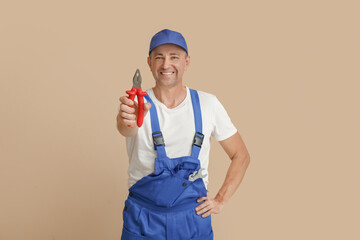 Portrait of male mechanic with pliers on beige background