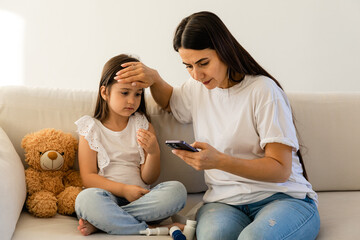 Mom, phone call and sick child on sofa with thermometer, telehealth and communication for advice. Healthcare, fever and mother with daughter on couch on mobile chat for medical consultation.