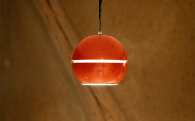 cool red orange vintage retro ceiling lamp in front of natural clay wall