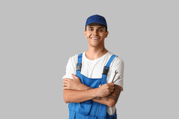 Male car mechanic with crossed arms and wrenches on grey background