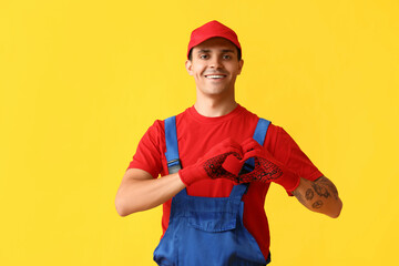 Male car mechanic showing heart gesture on yellow background