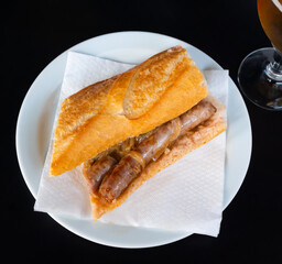 In fast food restaurant, appetizer of their fresh baguette with juicy pork sausages and fried...