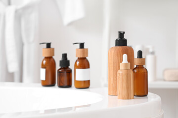 Cosmetic bottles on bathtub in room, closeup