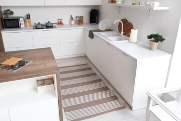 Stylish striped carpet on floor in kitchen