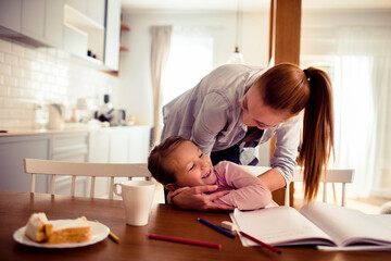 Loving young mother helping her daughter with homework at home
