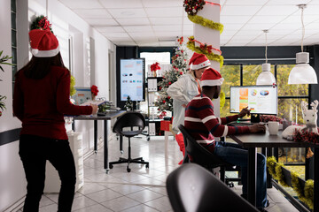 Multiethnical business team working with graphs in festive decorated office during Christmas...