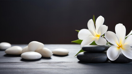 Fototapeta na wymiar Spa stones and frangipani flowers on black wooden background