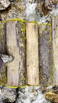 Slow motion 4K video POV view of Man's legs in trekking boots crossing mountain creek by wooden bridge during Makalu Barun National Park trek in Nepal. Mountain hiking and active people concept image.