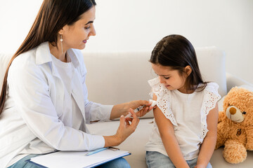 Doctor giving injection to little girl in hospital, closeup. Immunization concept