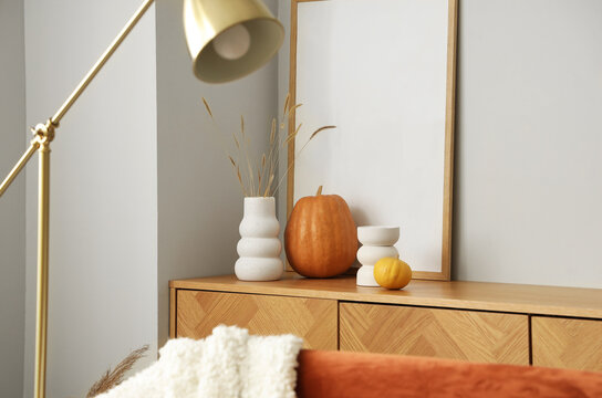 Vases with pumpkins and frame on chest of drawers in living room