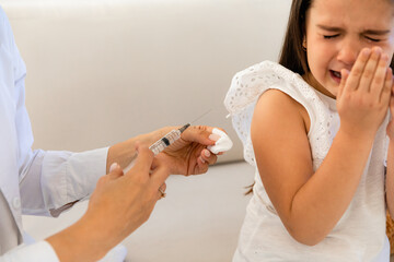 Doctor giving injection to little girl in hospital, closeup. Immunization concept. child is scared...