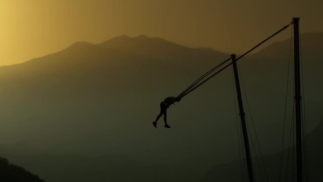 A Daring Man Who Loves Thrills and Adrenaline, He's Attached to a Bungee Cord in the Mountains and Gets Spun High in the Air. He Experiences Immense Pleasure and Moves His Legs as If Walking on Air, i