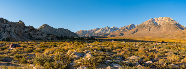 Fototapeta premium Views of Buttermilk Country at the foothills of the Sierra Nevada Mountains outside of Bishop, California. Large boulder, yellow fall foliage, and snow capped mountains.