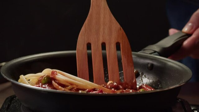 Chef cooking tomato Italian bolognese fresh pasta with tomato sause, man making traditional italian dinner on restaurant kitchen, tasty food