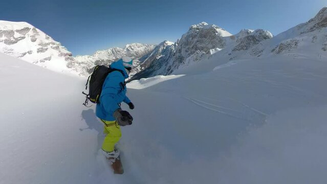 SELFIE: Snowboard tourist sprays fresh snow while riding down the snowy mountain on an adventure trip in beautiful Albanian Alps. He enjoys riding steep untouched terrains among snowed mountaintops.
