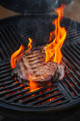 Barbecue dry aged wagyu prime rib beef steak grilled as close-up on a charcoal grill with fire and...