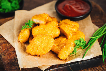 Semifinished Breaded chicken nuggets from chicken fillet on a dark background with fresh herbs.Fast food. Quick cooking at home. Breaded Chicken Inner Fillet. Fast cooking.Chicken nuggets with salad.