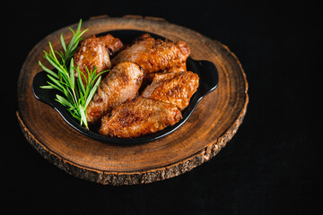 Chicken wings fried until half cooked, semi-finished product.Semi-finished chicken wings on a dark background.Half-finished. Quick cooking at home.Fast food.Semi-finished chicken wings lightly fried