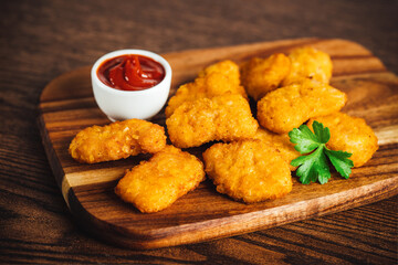 Breaded chicken nuggets. Semifinished chicken nuggets from chicken fillet on a dark background with fresh herbs. Quick cooking at home. Fast food. Breaded Chicken Inner Fillet.