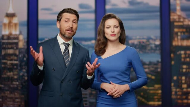 Couple hosts reporting breaking news in multimedia channel studio close up.